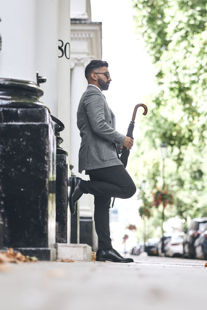Jaz in black trousers and grey jacket with black wholecuts depicting formal shoes for autumn