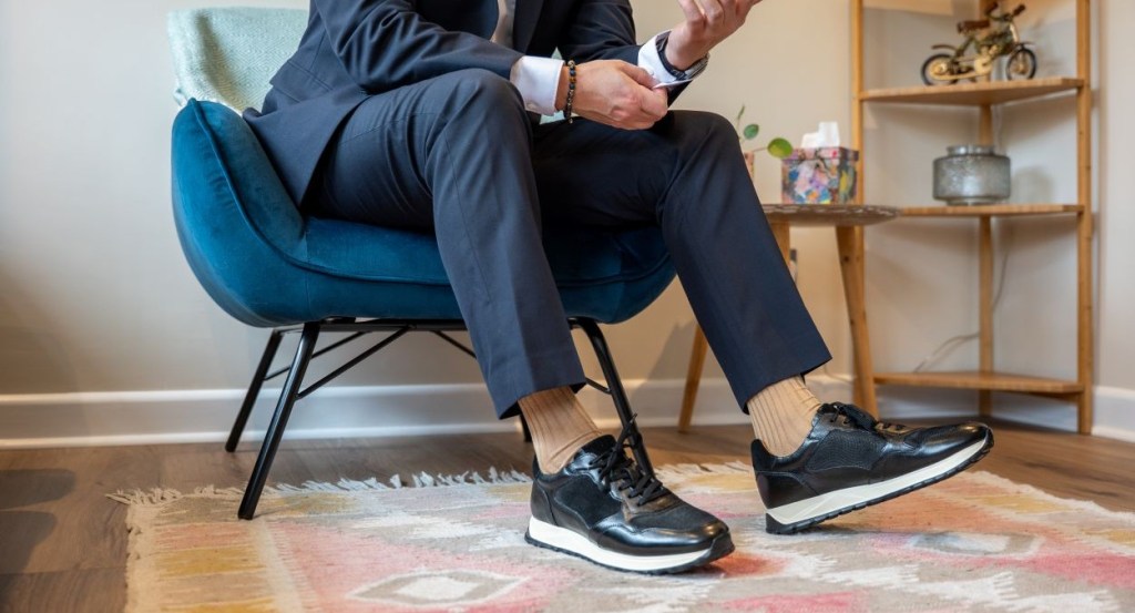 Man in navy sit, white shirt and black smart trainers
